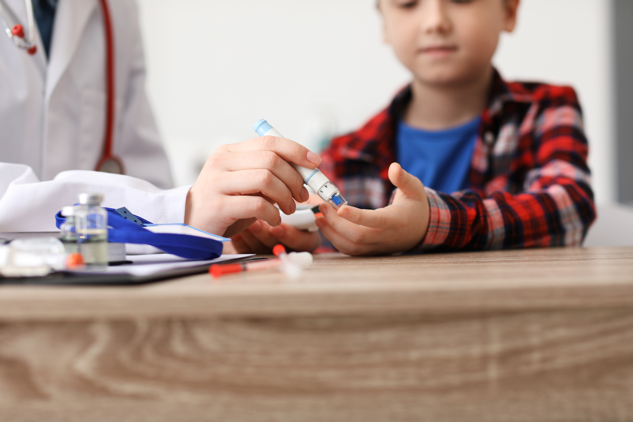 Doctor Taking Blood Sample of Diabetic Child in Clinic